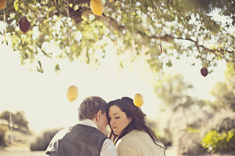 Bride and groom under lemon tree in engagement shoot
