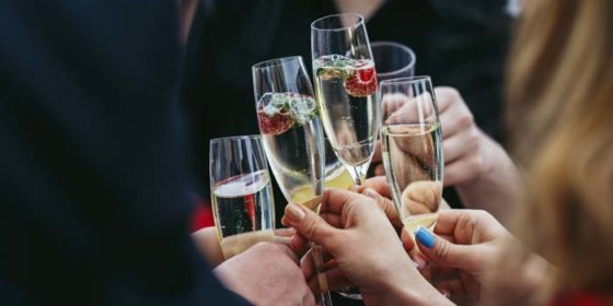 Guests clang glasses of champagne with delicious strawberries