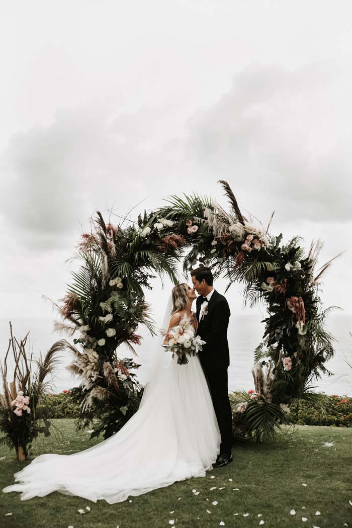 couple and floral arch at wedding