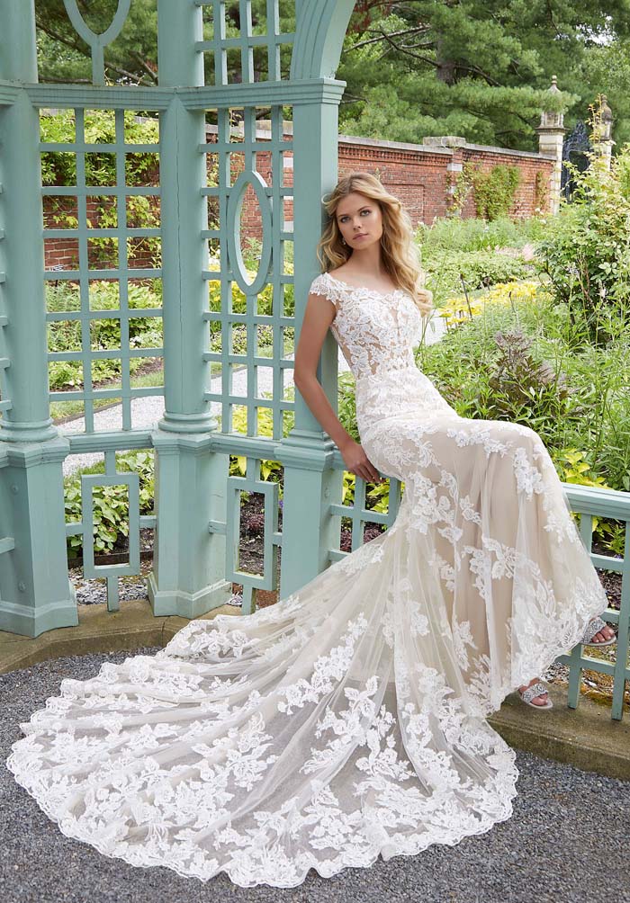 bride sitting down wearing wedding dress with long lace train